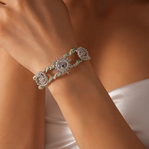 Detail of woven boho bracelet with silver sun pendant and rose accents on a model's wrist