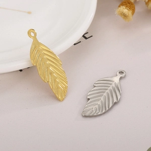 Detailed view of leaf-shaped stainless steel pendants in gold and silver finishes