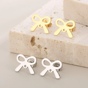 Detailed view of gold and silver hollow bow stud earrings on natural stone textures