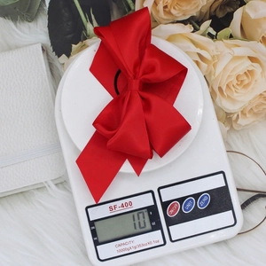Double layered red satin ribbon bow hair clip with high gloss finish on white fur background