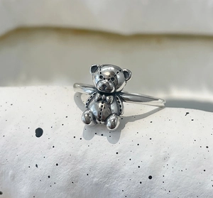 Detailed close-up of a vintage silver teddy bear ring with realistic texture and bowtie