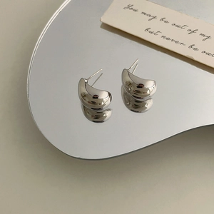 French style minimalist silver bead C-shaped stud earrings on reflective mirror surface