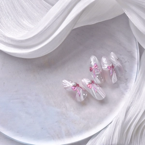 Détail de faux ongles nacrés dégradés avec nœuds 3D violets et petites paillettes d'étoiles