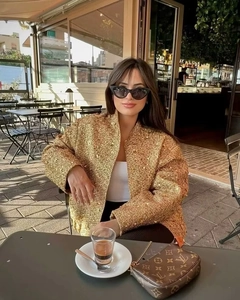 Giacca chic in tweed dorato con paillettes da donna indossata da modella in un caffè