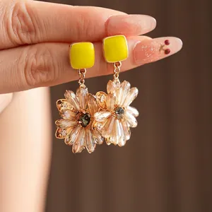 Handheld view of yellow square floral drop earrings with sparkling crystal petals