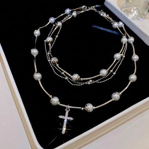 Double-layer grey pearl necklace with a sparkling rhinestone cross pendant on black velvet