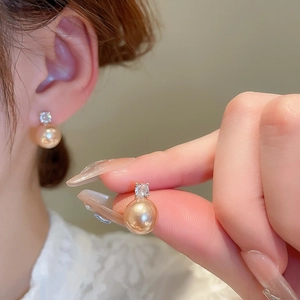 Gros plan de boucles d'oreilles perles dorées et zircons brillants sur l'oreille