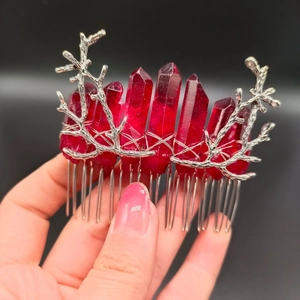 Detailed view of dark red crystal pillars on silver branch hair comb held in hand