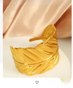 Detailed view of golden feather bangle with realistic leaf texture and polished finish