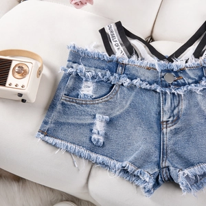 Dettaglio di pantaloncini di jeans blu con orli sfrangiati e spalline a righe su bianco