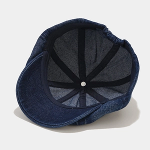 Inside view of dark blue denim newsboy cap with stitching and metal button details