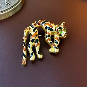 Detailed view of a vintage gold tiger brooch with orange enamel and green crystal eyes
