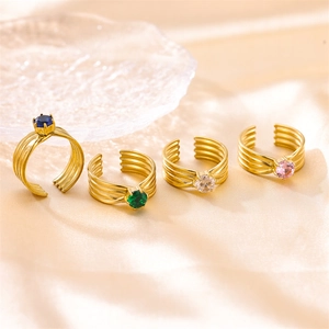 Anillos abiertos dorados de lujo con circonitas de colores sobre tela beige suave