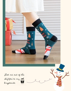 Close-up of a dark green Christmas sock with snowman and tree patterns on a model