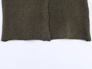 Dettaglio di un cardigan in maglia verde oliva con bottoni tondi e trama morbida