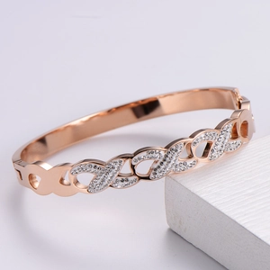 Detail of rose gold bangle with infinity pavé crystals on white marble prop
