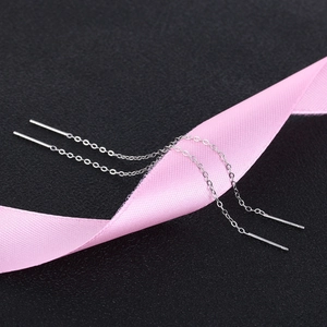 Macro detail of S925 sterling silver threader earrings draped on pink silk ribbon