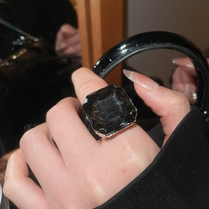 Close-up of a large square black stone set in a silver four-prong open ring for women