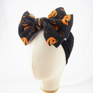 Macro detail of Halloween baby headband with pumpkin patterns and oversized bow texture
