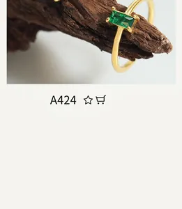 Close-up of a gold ring with a rectangular green emerald set on a natural wood branch