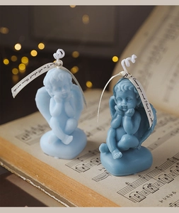 Detailed view of light and dark blue cherub angel soy candles on vintage music sheet