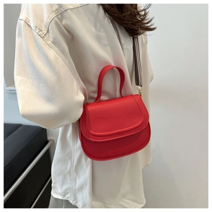Detail of red PU leather shoulder bag with striped woven strap and flap closure design
