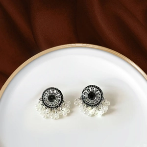 Macro detail of ethnic-style pearl drop earrings on a minimalist white tray