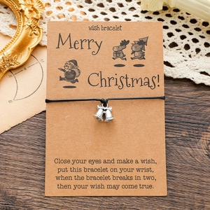 Detailed view of Christmas wish bracelet with silver bell charm on a vintage kraft card