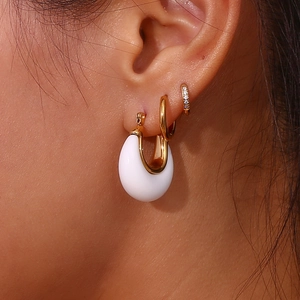 Close-up detail of white teardrop earring and gold pavé mini hoop on a model