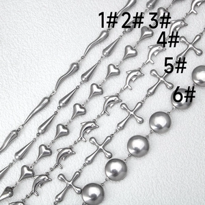 Macro shot of stainless steel DIY chains with heart and dolphin pendants on white leather
