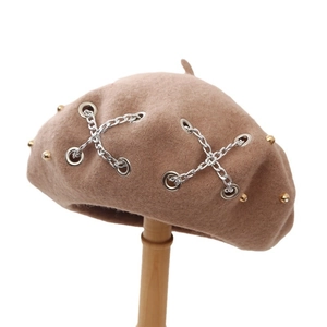 Khaki wool beret hat with silver chains and gold rivet details on a mannequin stand