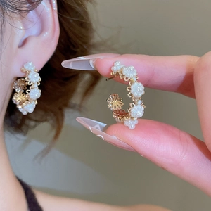 Detailed view of gold hoop earrings featuring elegant white pearl flower petals