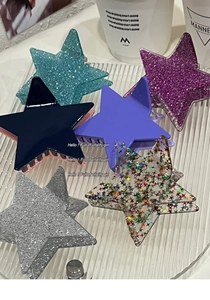 Close-up of sparkling star-shaped hair claws in various glitter finishes on a tray
