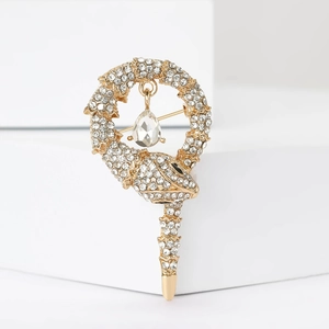Detail of a golden snake brooch with sparkling rhinestones and a teardrop pendant