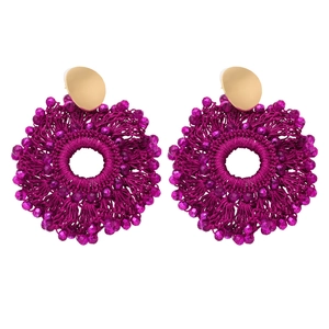 Detail view of pink hand-woven bohemian hoop earrings with beads and gold metal studs