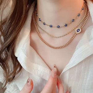 Close-up of layered gold evil eye necklaces with rhinestones on a model's neck