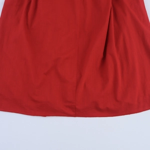 Vue détaillée de la texture en coton rouge et des coutures de l'ourlet sur cette robe d'été