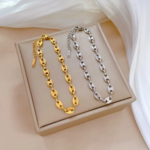 Minimalist gold and silver pig nose link bracelets displayed on a beige jewelry box