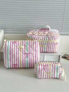 Detailed macro of the pink striped quilted makeup bag set with purple bow embroidery