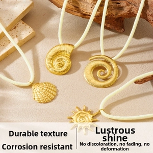 Détail de pendentifs nautile dorés avec cordes tressées sur un décor de plage naturel