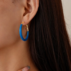 Detail of blue and gold geometric hoop earring on model with polished enamel finish