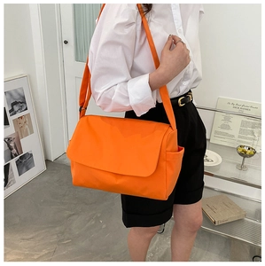 Close-up of bright orange oxford cloth messenger bag with adjustable wide strap