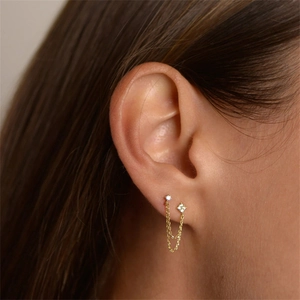 Elegant gold double piercing chain earrings with white zircon accents on a female model