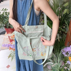 Détail du sac cabas en toile vert clair avec poche intérieure zippée et fermoir magnétique