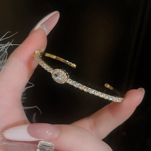 Macro shot of gold-plated bangle with oval zircon center and micro-pave detailing