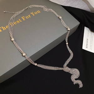 Detailed shot of multi-layer silver chain necklace with knot tassel on a gift box