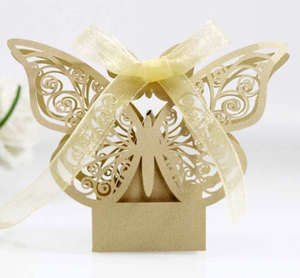 Macro detail of golden laser-cut butterfly wedding favor box with organza ribbon bow