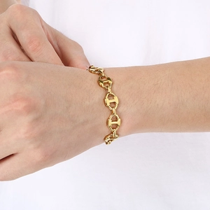 Close-up of polished gold-finished stainless steel H-link chain bracelet on a model wrist