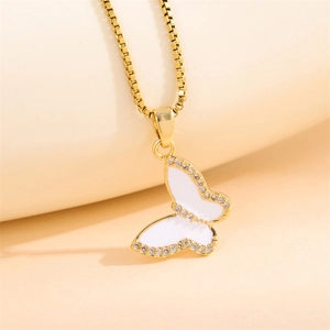 Golden butterfly necklace with white enamel and sparkling zircon on a warm background