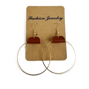 Minimalist gold metal hoop earrings with brown leather splice accents on a display card